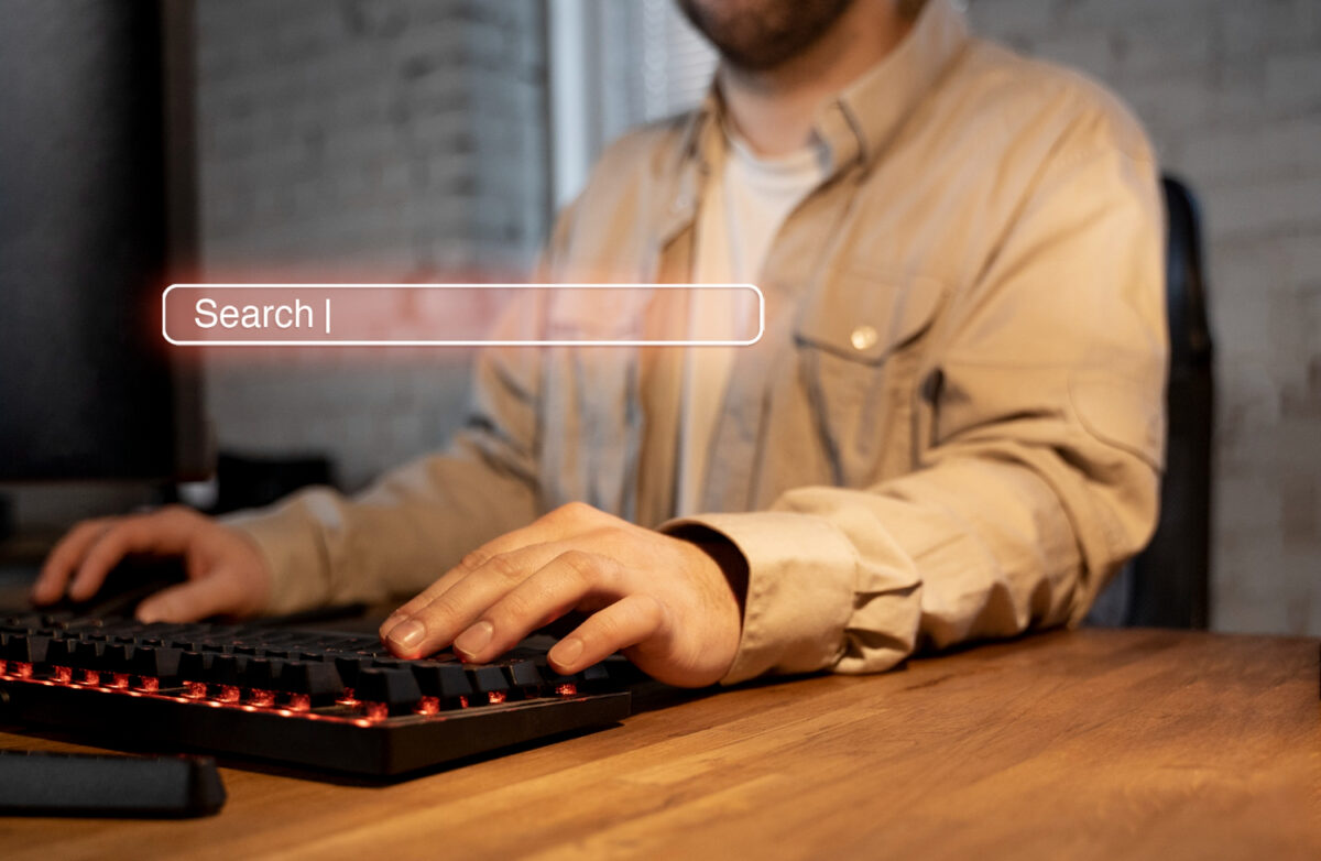 Homme tapant sur un clavier rétroéclairé avec une barre de recherche virtuelle affichée au premier plan