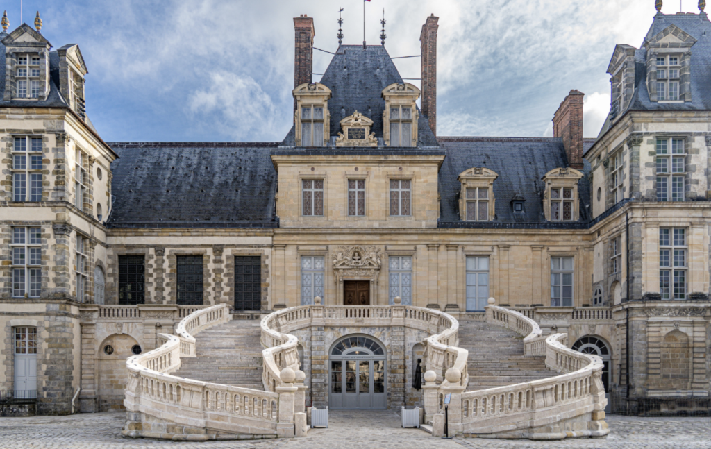 Façade du château de Fontainebleau avec son célèbre escalier en fer à cheval en pierre blanche et sa cour pavée