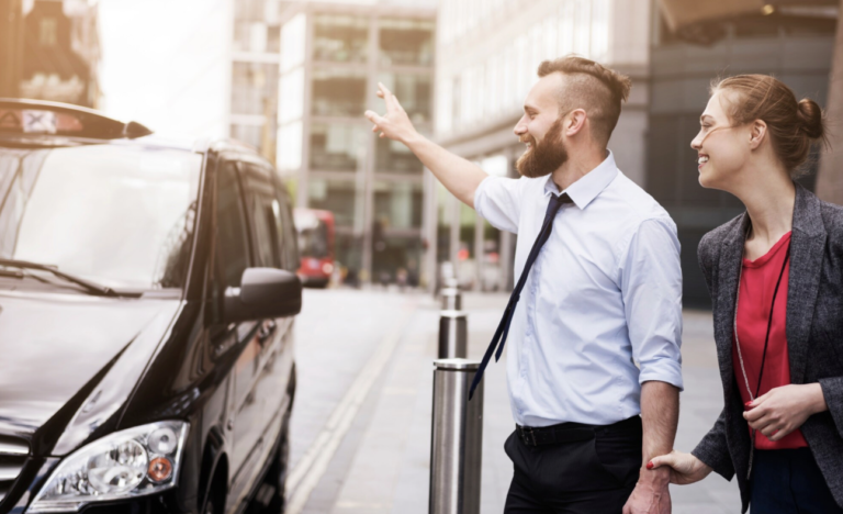 Un homme et une femme souriants hèlent un taxi noir dans une rue de ville
